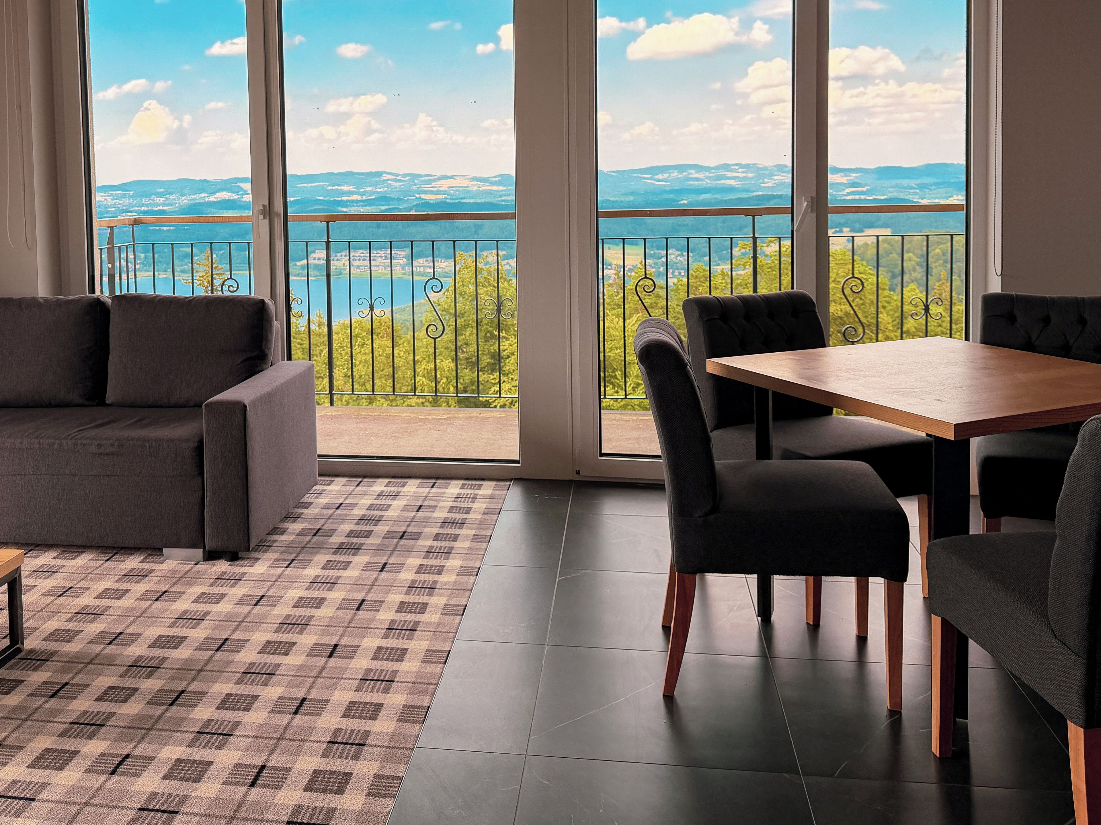 Habitación con sofá, mesa de comedor, sillas y vistas a través de amplios ventanales.