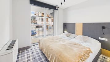 Un dormitorio moderno con una cama grande, una ventana con vistas a edificios y una lámpara en el techo.