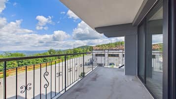 A balcony with a view of a green landscape and a clear sky.