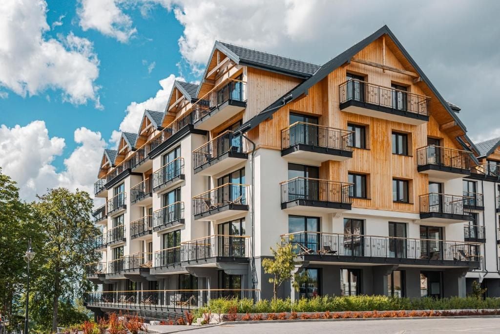 A multi-story hotel with balconies, a flat roof, and a landscaped garden area.