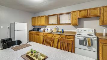 A kitchen with wooden cabinets, a refrigerator, a stove, and a dining table with a placemat.