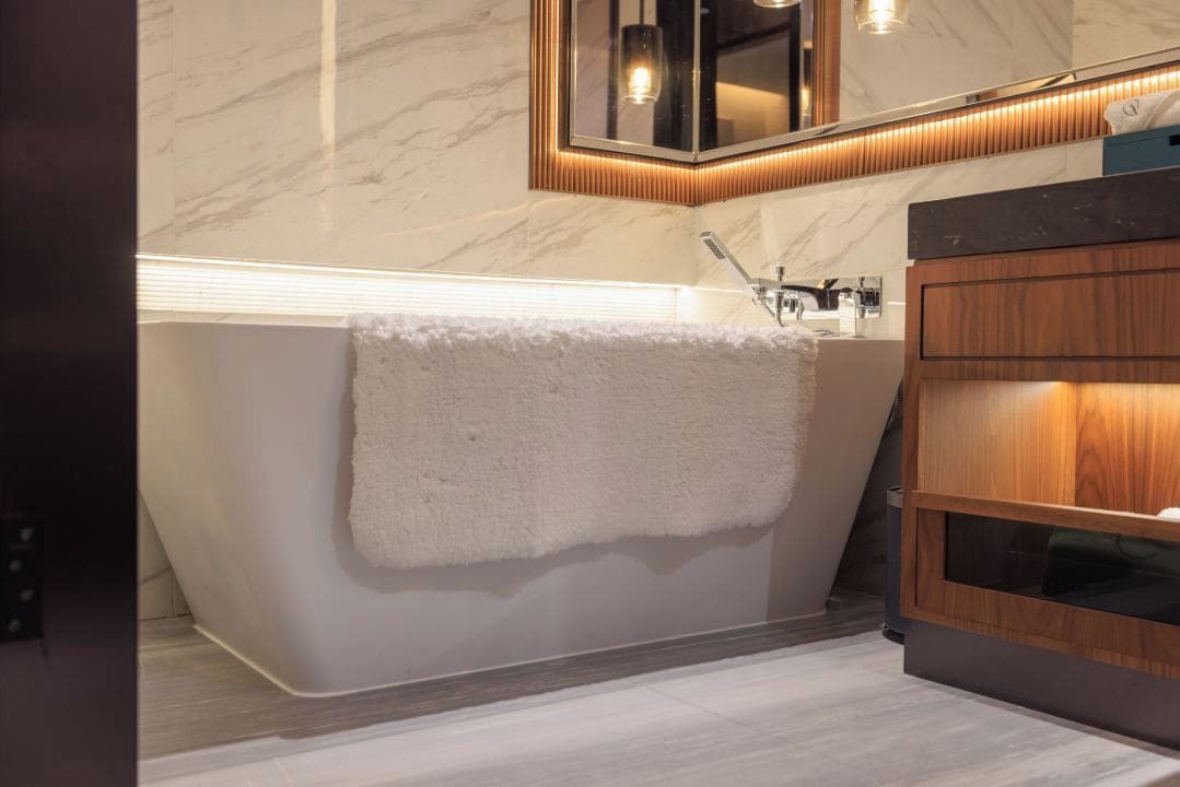 Ein modernes Badezimmer mit einer freistehenden Badewanne, einem Holzkosmetikschrank und einem Spiegel über dem Waschbecken.