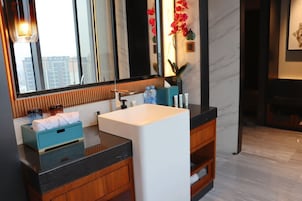 Un baño moderno con un espejo grande, un lavabo blanco y armarios de madera.