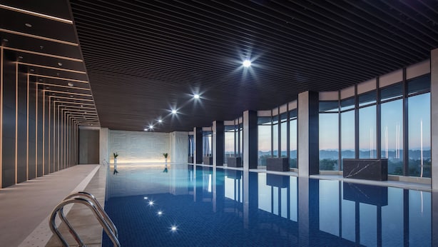 A modern indoor swimming pool with a clear view of the city skyline through large windows. - Grand Skylight InternationalHotelXinfeng (Ganzhou)