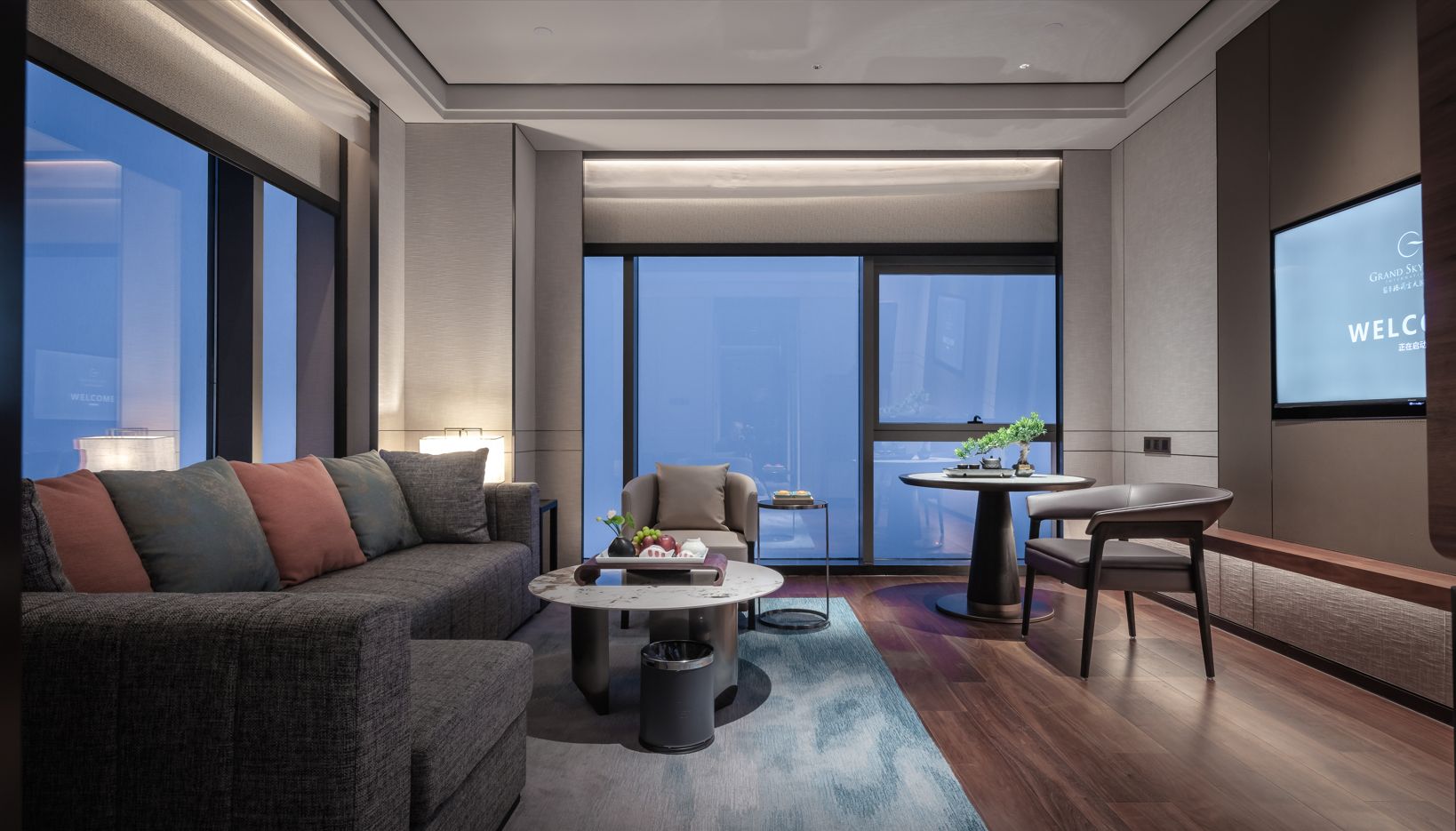 A modern hotel room with a sofa, coffee table, and dining table.