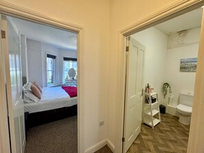 A bedroom with a bed, a window, and a bathroom with a toilet and shelves. - Our 2 Bedroom Flat  located in the heart of the town centre (Bournemouth)
