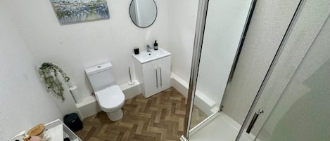 A bathroom with a toilet, sink, and shower area.