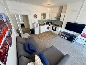 A compact living space with a sofa, a television, a kitchen area, and a dining table. - Our 2 Bedroom Flat  located in the heart of the town centre (Bournemouth)