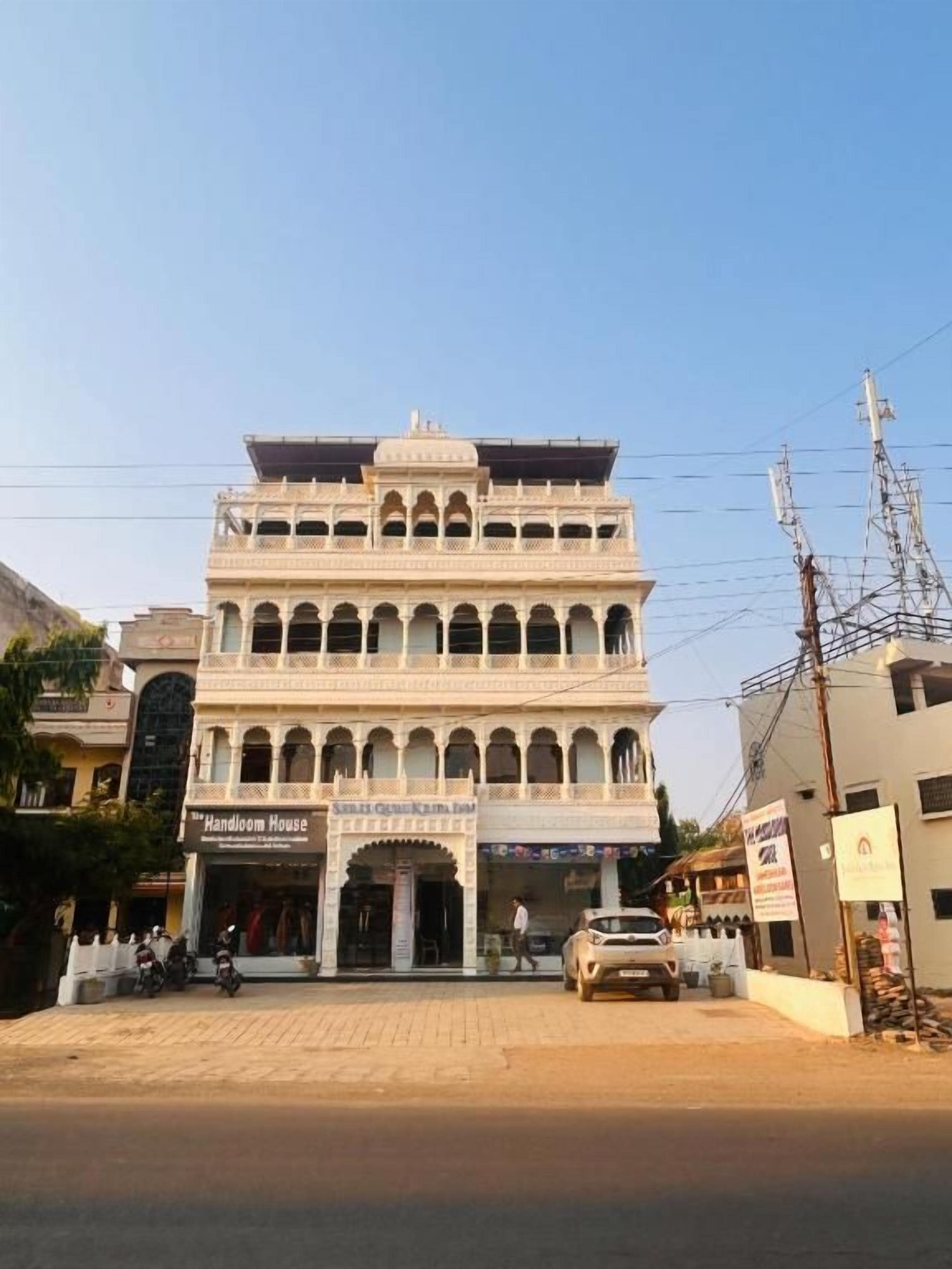 Un edificio de varios pisos con una entrada central, balcones y un letrero que dice 'Handloom House'.