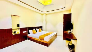 Habitación de hotel con cama, espejo, luz en el techo y una pequeña mesa con una silla.