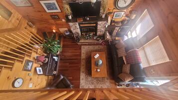 A wooden interior with a fireplace, a sofa, a coffee table, and a staircase.