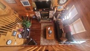 A wooden interior with a fireplace, a sofa, a coffee table, and a staircase.
