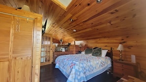 Un dormitori de cabana de fusta amb un llit, una petita habitació i una porta amb finestre.