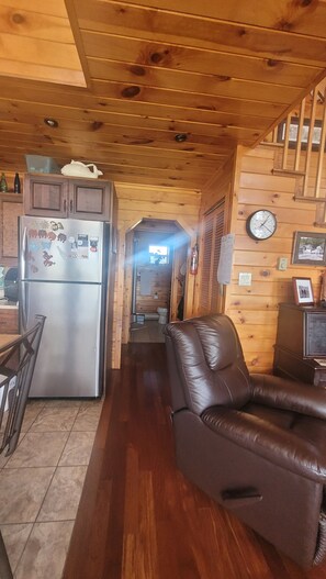 Un interior de madera con cocina, una sala de estar con sofá de cuero y un baño a la vista.