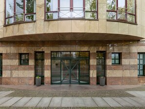 Un edificio con entrada curva, amplias puertas de cristal y fachada de piedra.