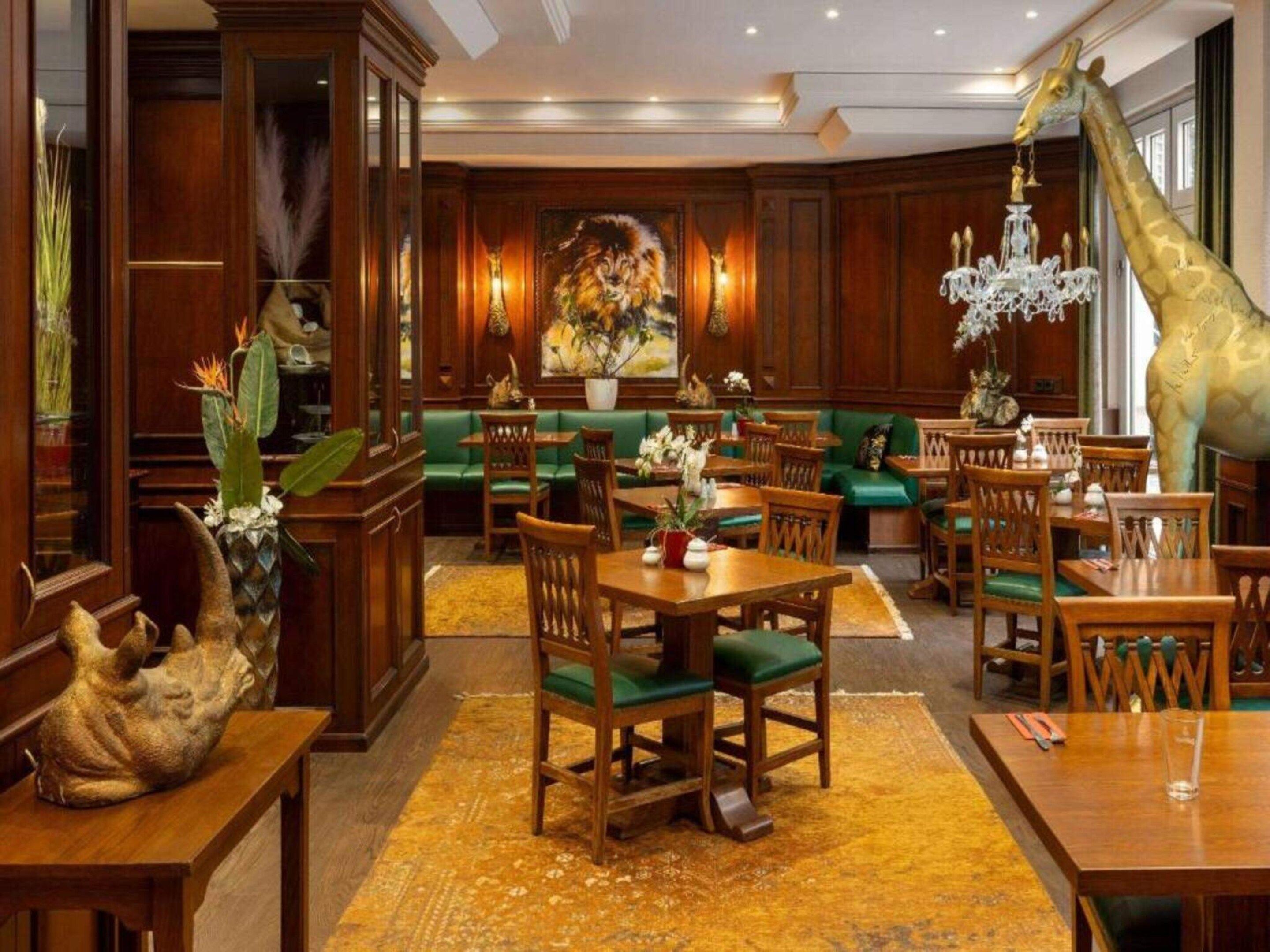 A hotel lobby with wooden furniture, a giraffe statue, and a lion painting.
