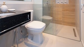 A modern bathroom with a glass-enclosed shower, a white toilet, and a black countertop with a soap dispenser. - Corporate Stays First del Sol - 307 (Asunción)