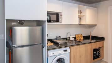 Une cuisine moderne équipée d’un lave-linge encastré, d’un four à micro-ondes et d’un réfrigérateur en acier inoxydable.