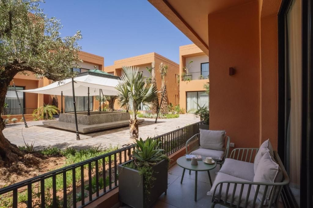 Un balcón con mobiliario exterior, una zona de estar cubierta y vistas a edificios cercanos.