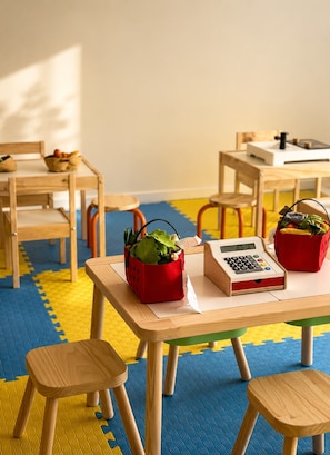 Et klasseværelse med træmøbler, en lommeregner og kurve med planter.
