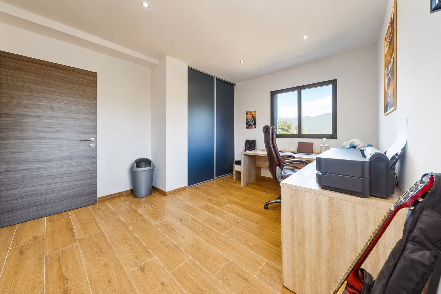 A modern office space with a desk, chair, and a guitar.