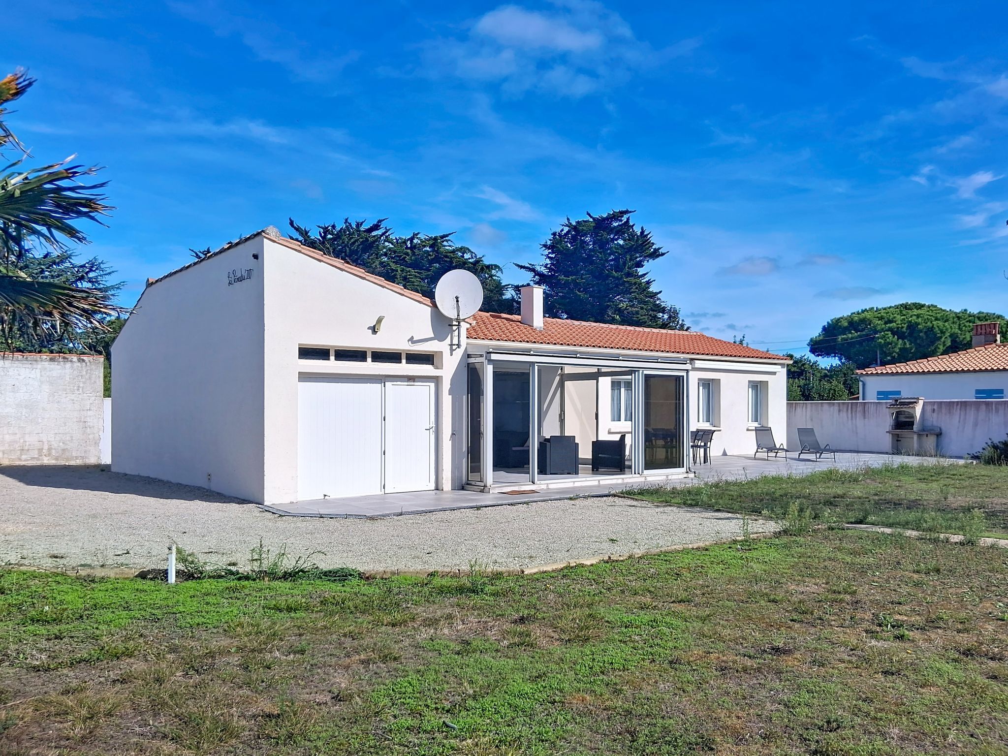 Ein Bungalow mit Garage, überdachter Sitzgelegenheit und Satellitenschüssel.