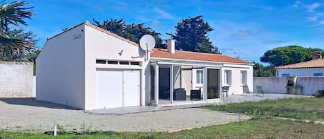 Ein Bungalow mit Garage, überdachter Sitzgelegenheit und Satellitenschüssel.