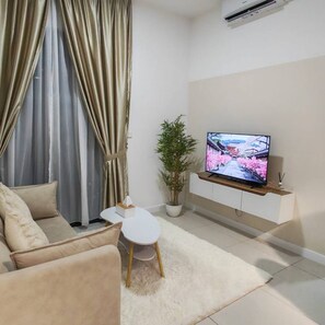 Ein Wohnzimmer mit einer Couch, einem kleinen Tisch, einem Blumentopf und einem an der Wand befestigten Fernseher.