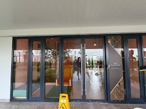 A building entrance with glass doors, a caution sign, and a sign indicating a kids playroom. - Skyline A-36-01, heart of the city with car park (Kuala Lumpur)