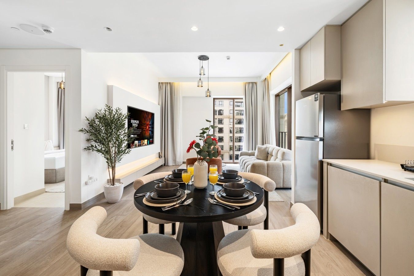 Un comedor moderno con una mesa redonda, sillas y una cocina al fondo.