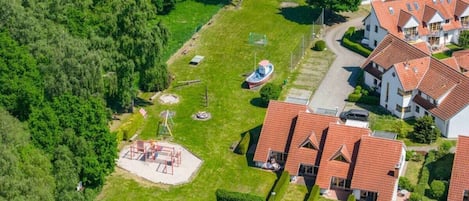 Vista aérea de una zona residencial con casas, un parque infantil y un barco.