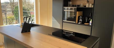 Cocina moderna con isla central, horno integrado y vistas al exterior.