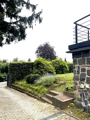 A stone pathway leading to a building with a metal staircase and a stone wall. - My Time in the Harz Mountains - Your Vacation Home in the Harz Mountains. With a sauna and barbecue area. (Goslar)