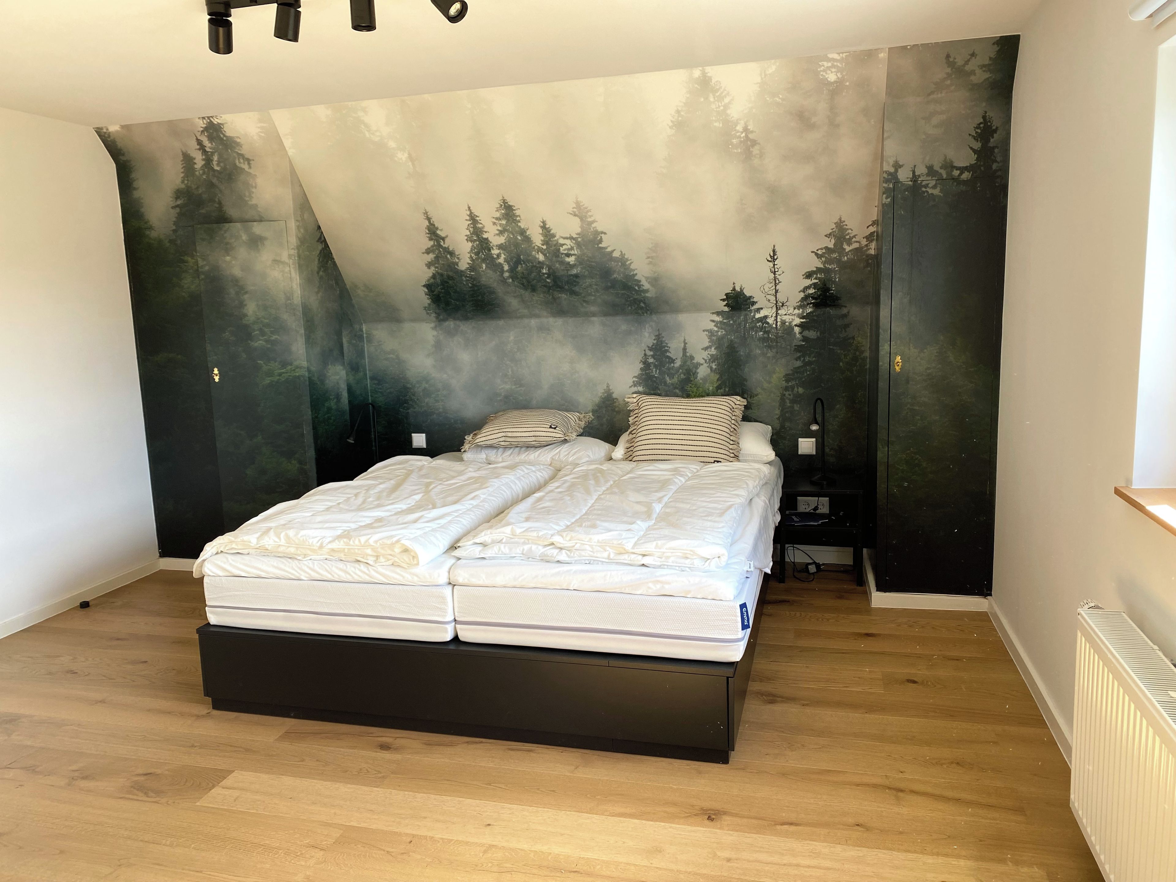 A bedroom with a bed, a nightstand, and a wall mural.