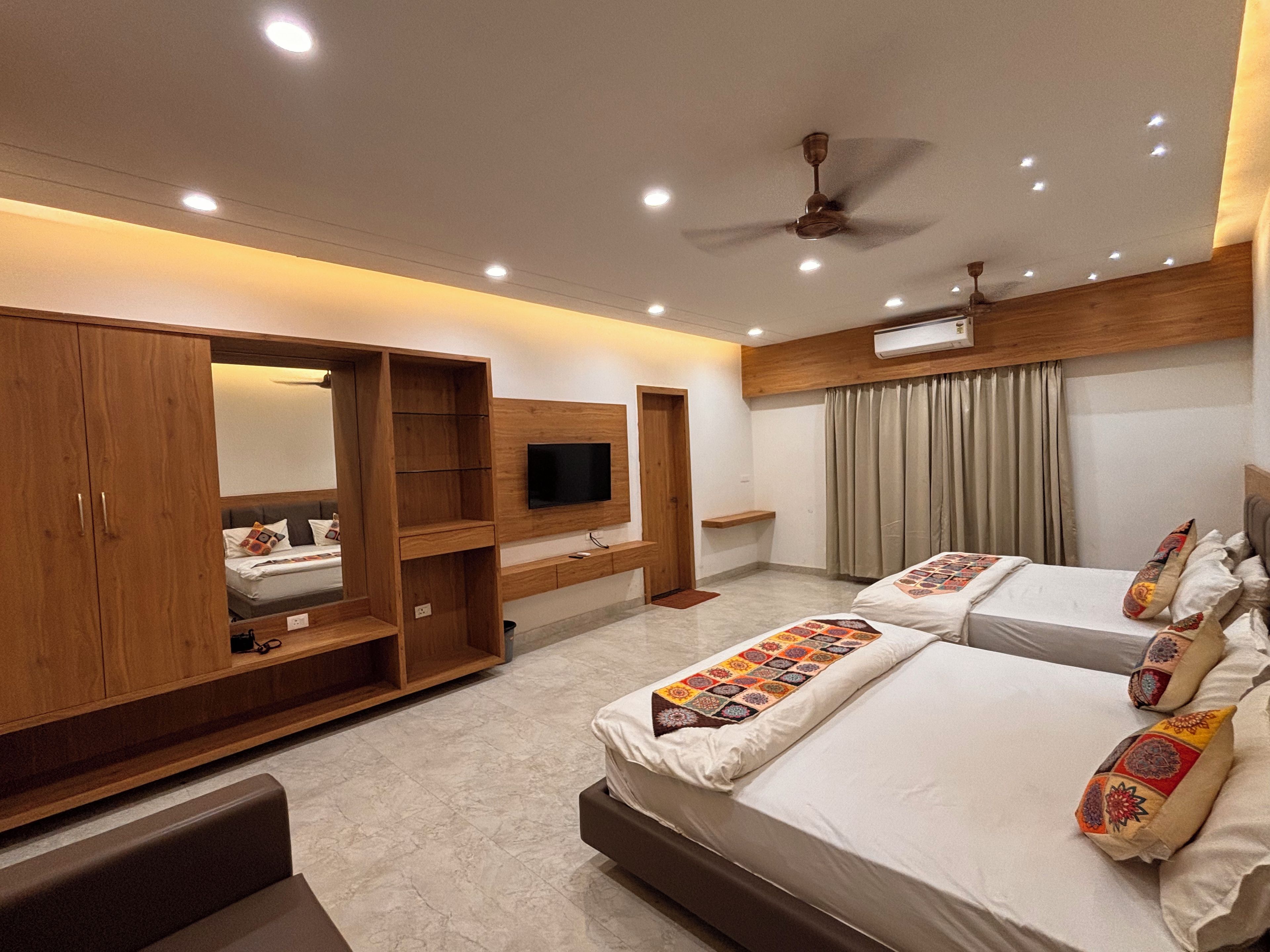 A hotel room with a bed, a TV, a wardrobe, and a ceiling fan.