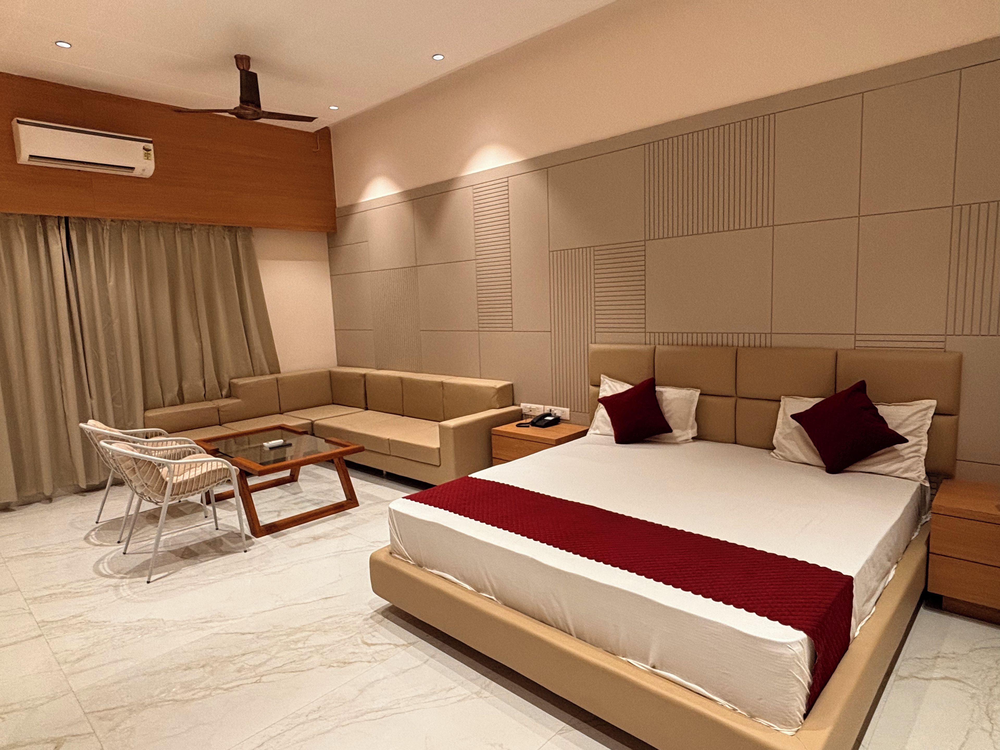 Una habitación de hotel moderna con una cama grande, un sofá, una mesita y una silla.