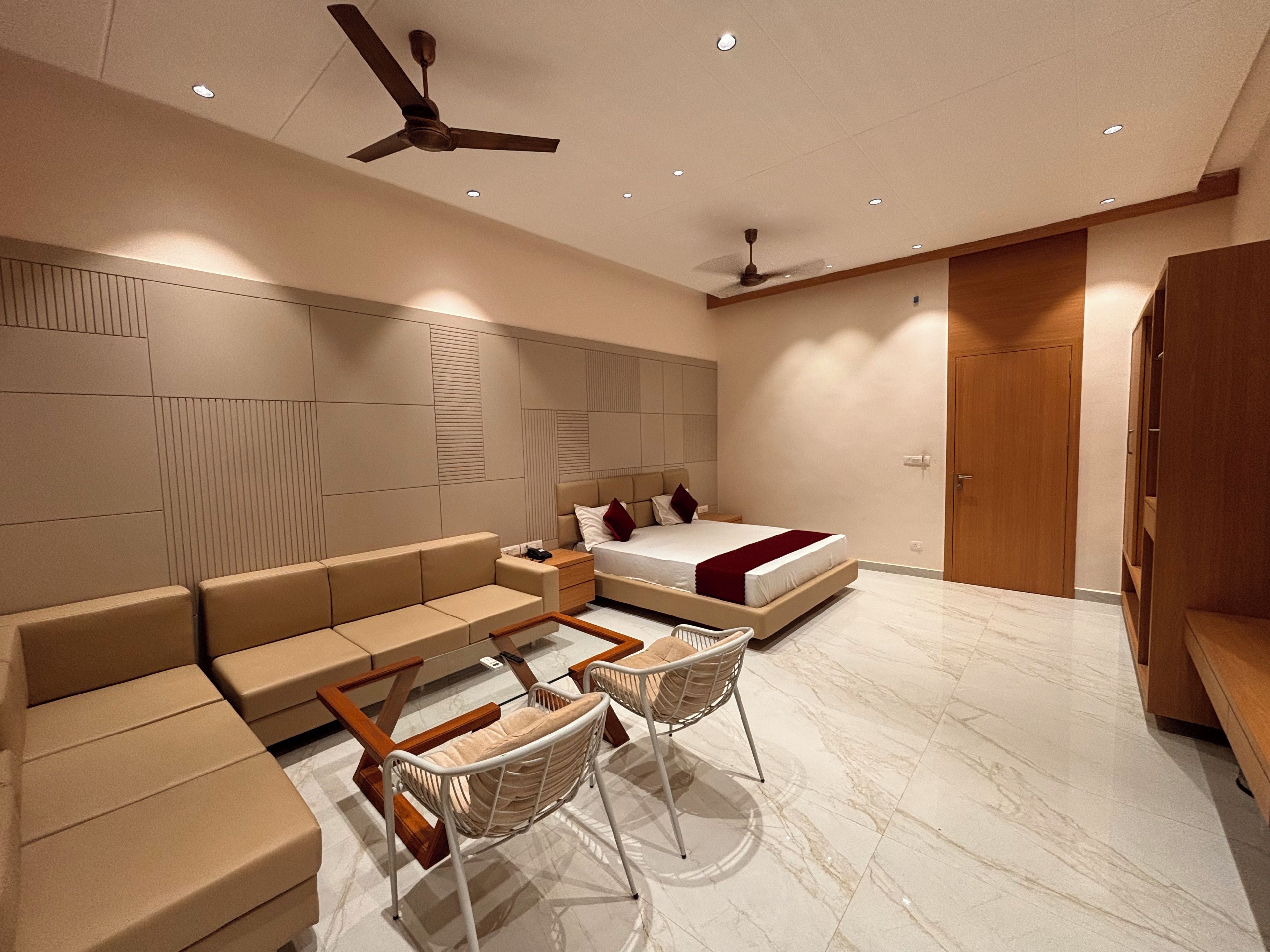 Quarto moderno com sofá, duas poltronas, cama e ventilador de teto.