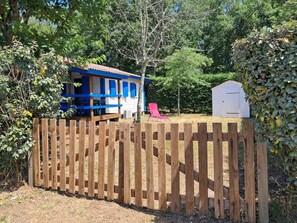 A wooden fence, a blue and white structure, and a white shed. - chalet cosy-mer-piscine (Lanton)