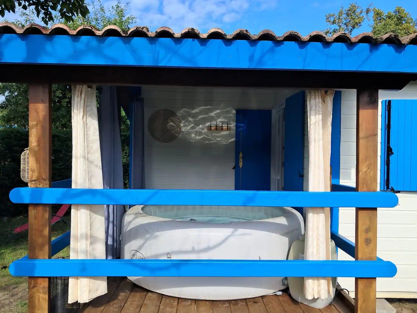 A small outdoor hot tub area with a blue roof and wooden structure.