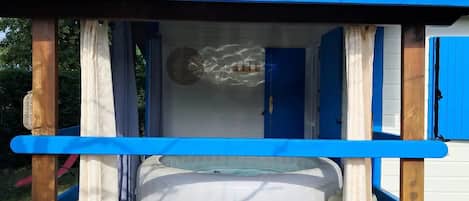 A small outdoor hot tub area with a blue roof and wooden structure.