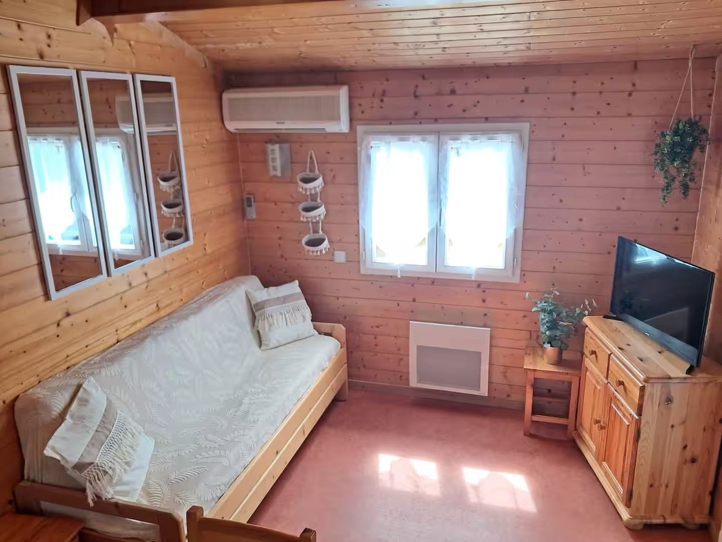 A wooden cabin with a sofa, a television, and a small cabinet.