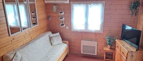 A wooden cabin with a sofa, a television, and a small cabinet.
