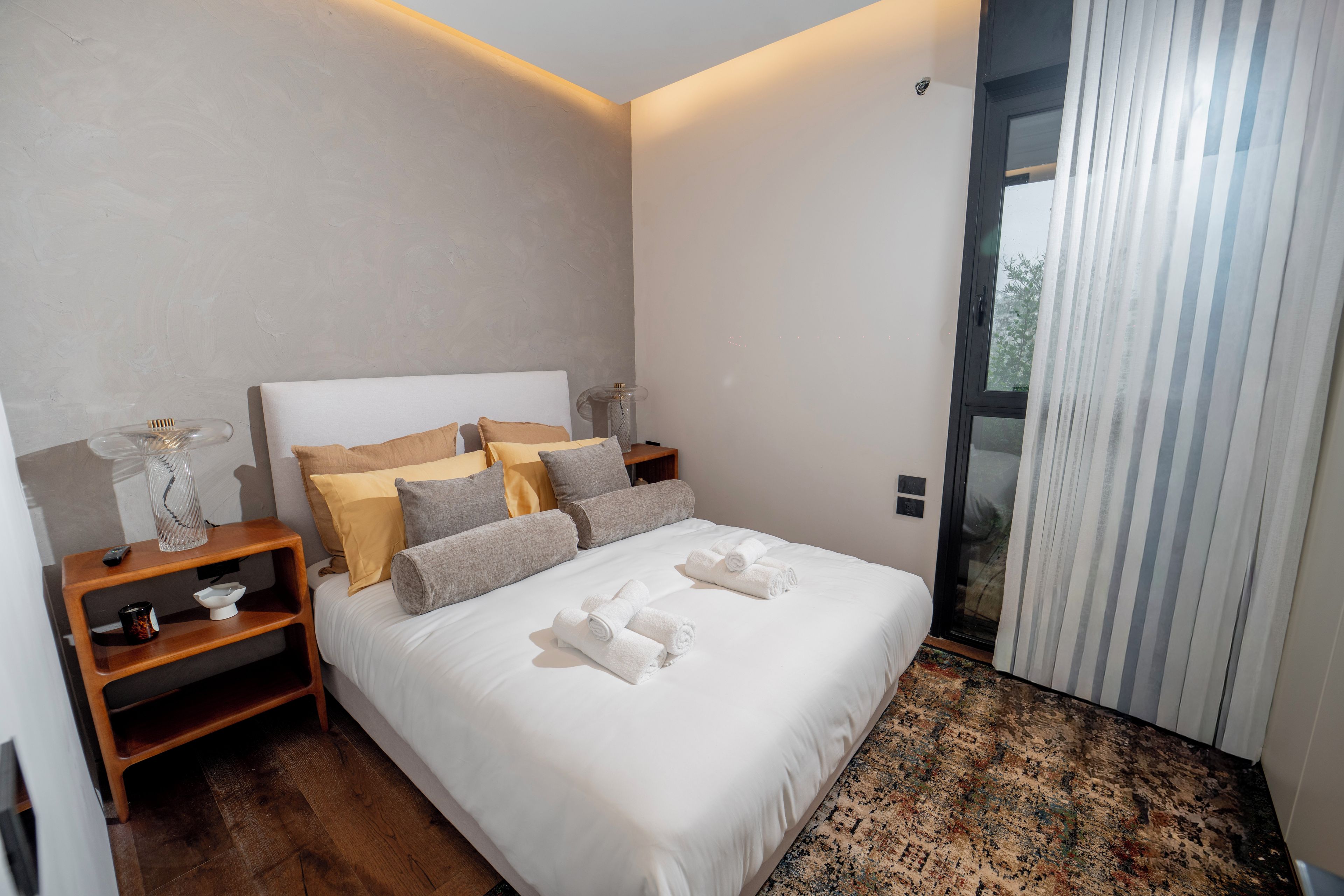Een moderne slaapkamer met een groot bed, nachtkastjes en uitzicht door een schuifdeur.