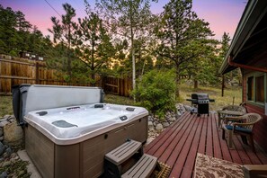 Un bain à remous sur une terrasse en bois, avec vue sur une zone boisée.