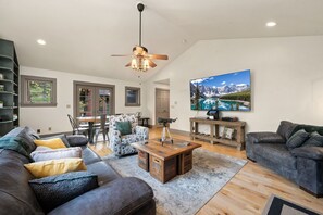 Un salon spacieux avec un grand canapé, une table basse et un téléviseur fixé au mur.