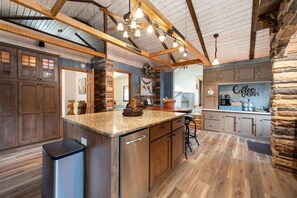 A kitchen with a granite countertop, stainless steel appliances, and a stone accent wall.