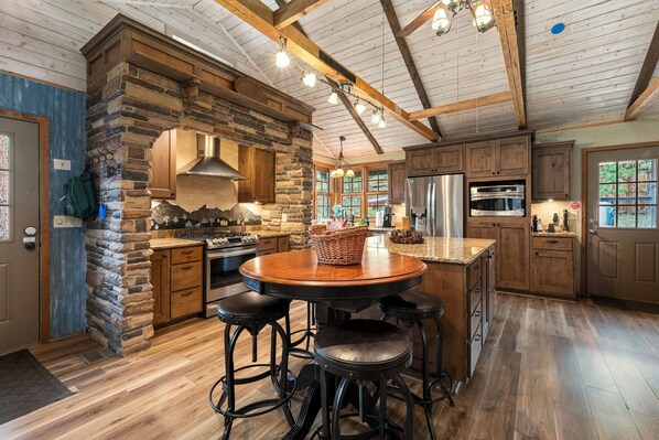A spacious kitchen with a stone accent wall, modern appliances, and a central island with stools.