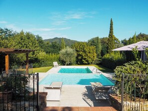Et rektangulært pool med to liggestole og et pergola.