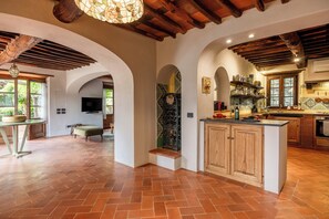 A spacious kitchen with a central island, wooden cabinets, and a tiled backsplash.