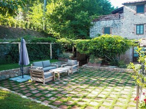 A patio with outdoor furniture, a pergola, and a stone wall.